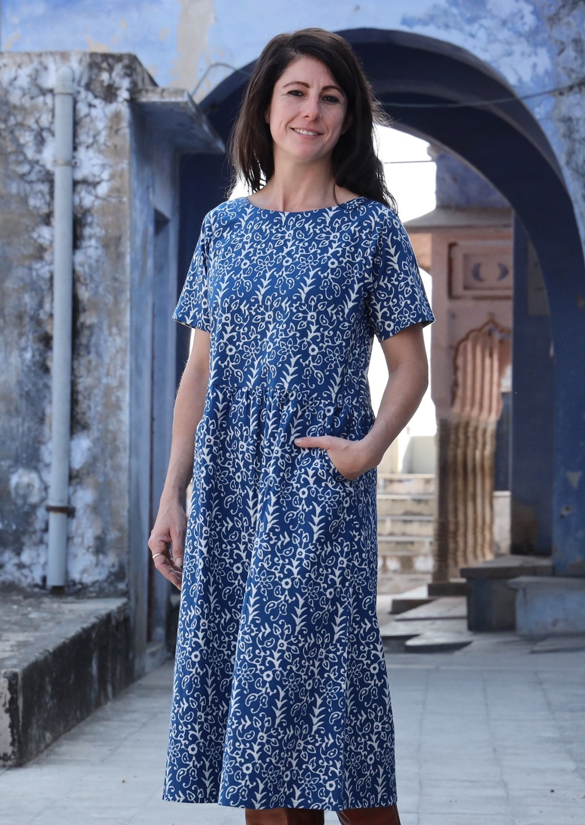 Woman smiling with one hand in pocket wearing 100% cotton blue and off white Maddison dress