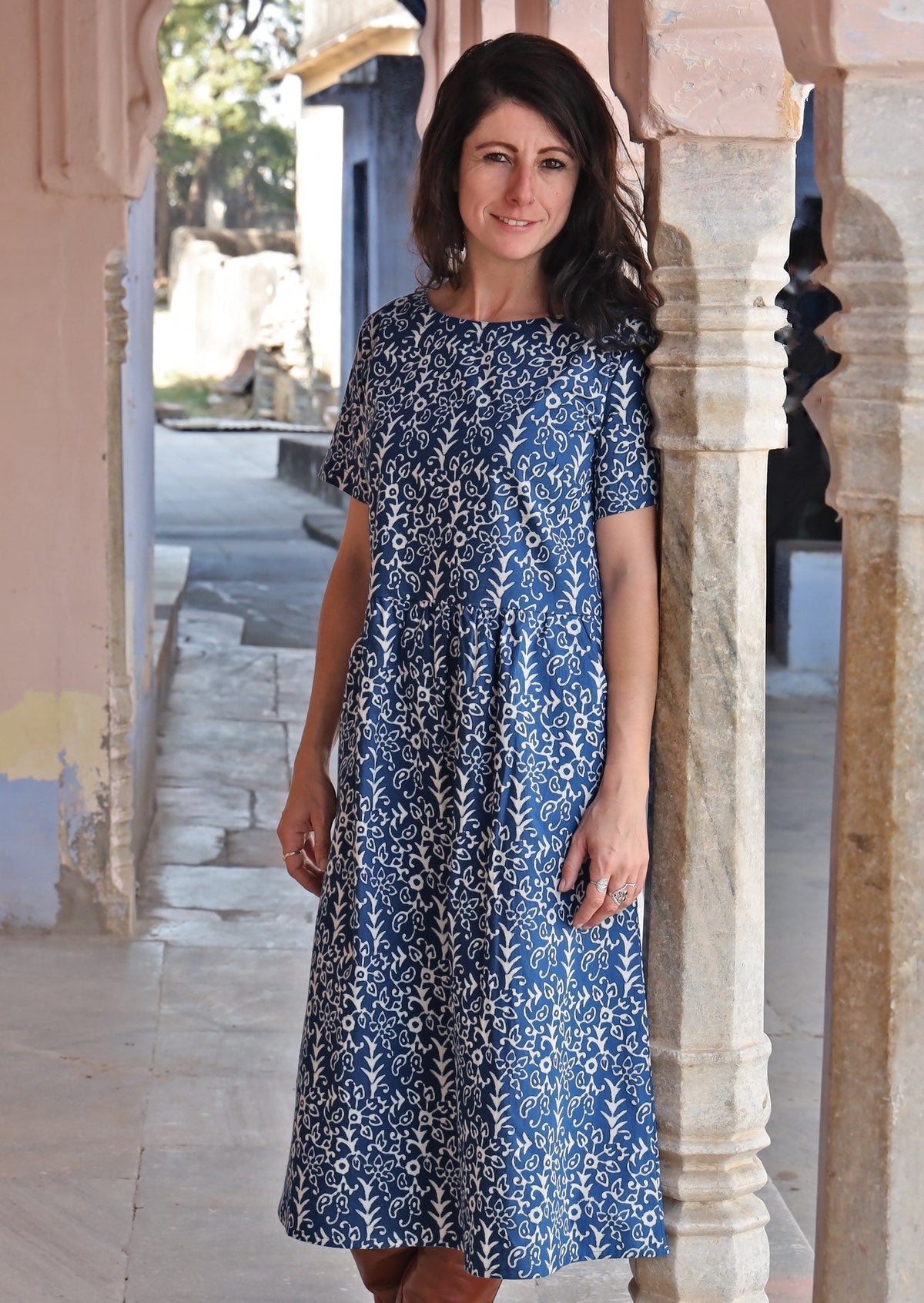 Woman leaning on pillar wearing 100% cotton blue base and off white floral Maddison dress