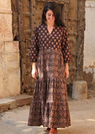 Model wearing a cotton three tiered maxi dress with combination of two floral prints on earthy brown base, 3/4 sleeves and buttoned bodice.