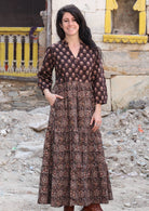 Model wearing a 3 tiered cotton maxi dress in combination of two earthy floral prints with a hand in pocket.