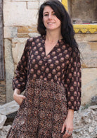 Closeup of model wearing a 3 tiered cotton dress with buttoned bodice and mandarin collar