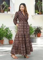 Model with hands in pocket wears cotton maxi dress in two earthy brown based floral print.
