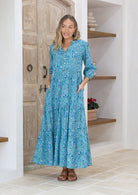 Woman with both the hands in pocket wears 3 tiered maxi dress with mandarin collar and V neckline.