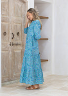 Model posing slight sideways in 3/4 sleeved long maxi dress with buttoned bodice and pockets.