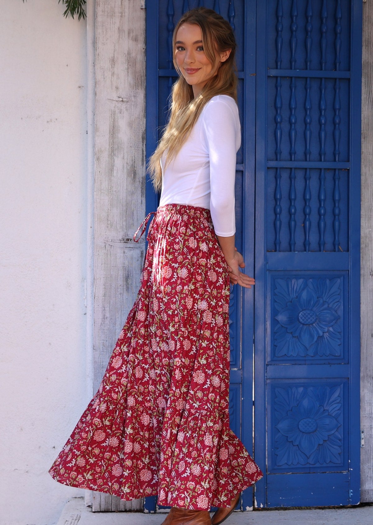 Side pose of model wearing bright red cotton maxi skirt with elasticated waist and drawstring .