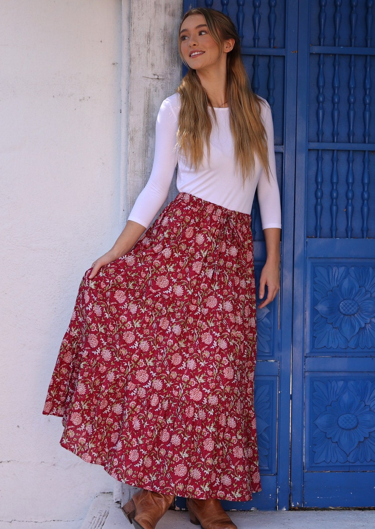 Model flaunting crinkled cotton skirt in bright red colour with hints of pink, green and white floral design on it.