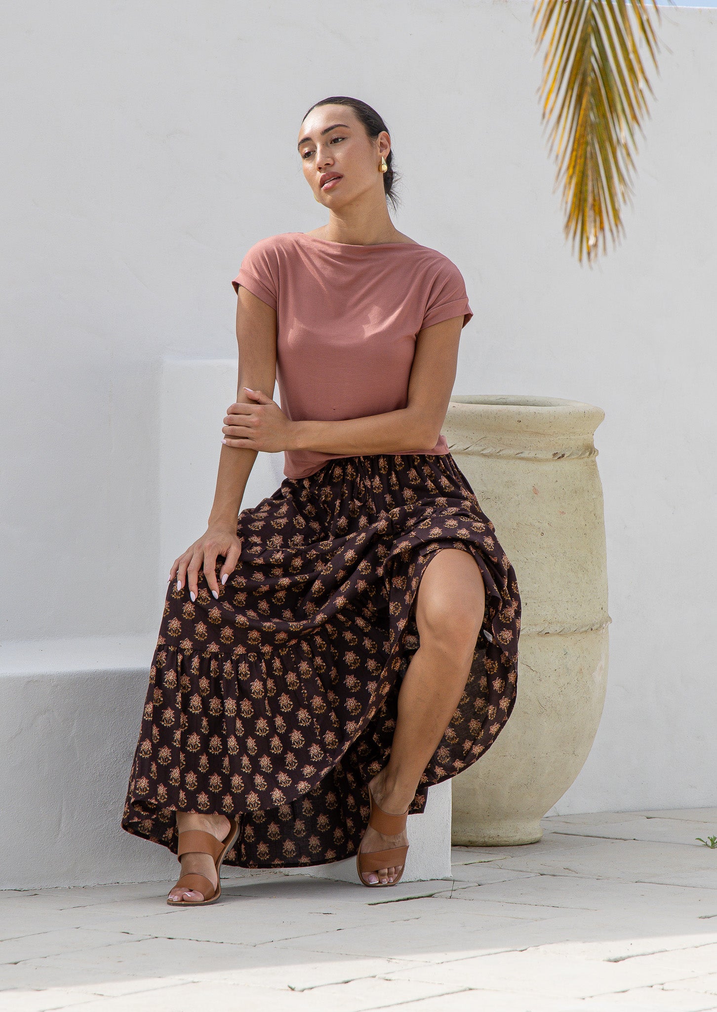 Woman wearing 100%^ cotton flowy maxi skirt in brown based floral print with elasticated waist and drawstring.