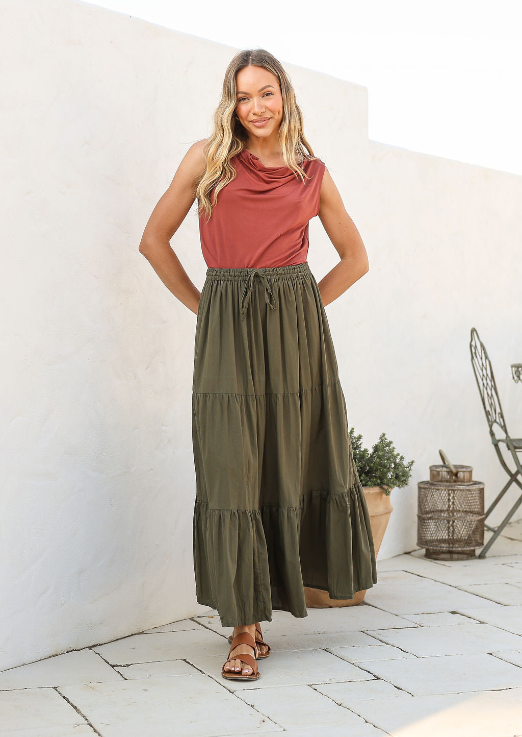 Woman wearing a pink top and olive green skirt with elasticated waistband standing outdoors