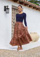 Model wears 100% cotton tiered maxi skirt with earthy floral print on rust base.