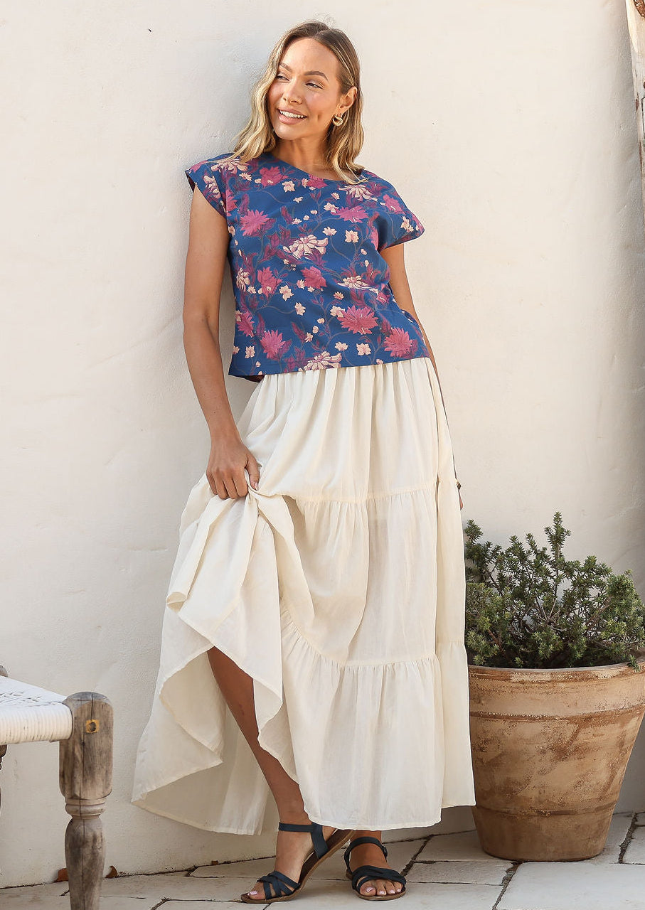 women wearing a 100% cotton white skirt with a blue printed top standing against a white background.