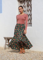 Model pairing a 100% cotton floral printed maxi skirt in deep green with a long sleeve stretch top in dusty pink.