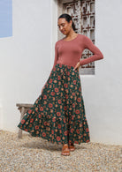 Model poses in 100% cotton maxi skirt with elasticised waist and drawstring in deep green based floral print.