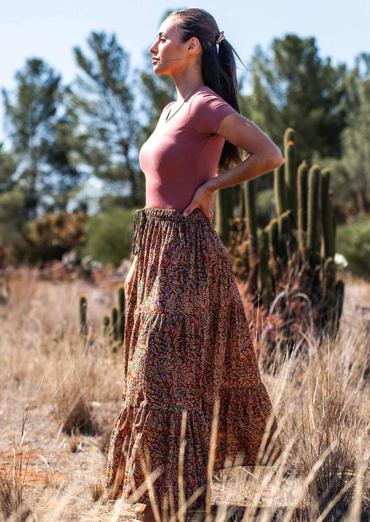 Woman stands with hand on hip in warm toned cotton maxi skirt and dusty rose stretch rayon top
