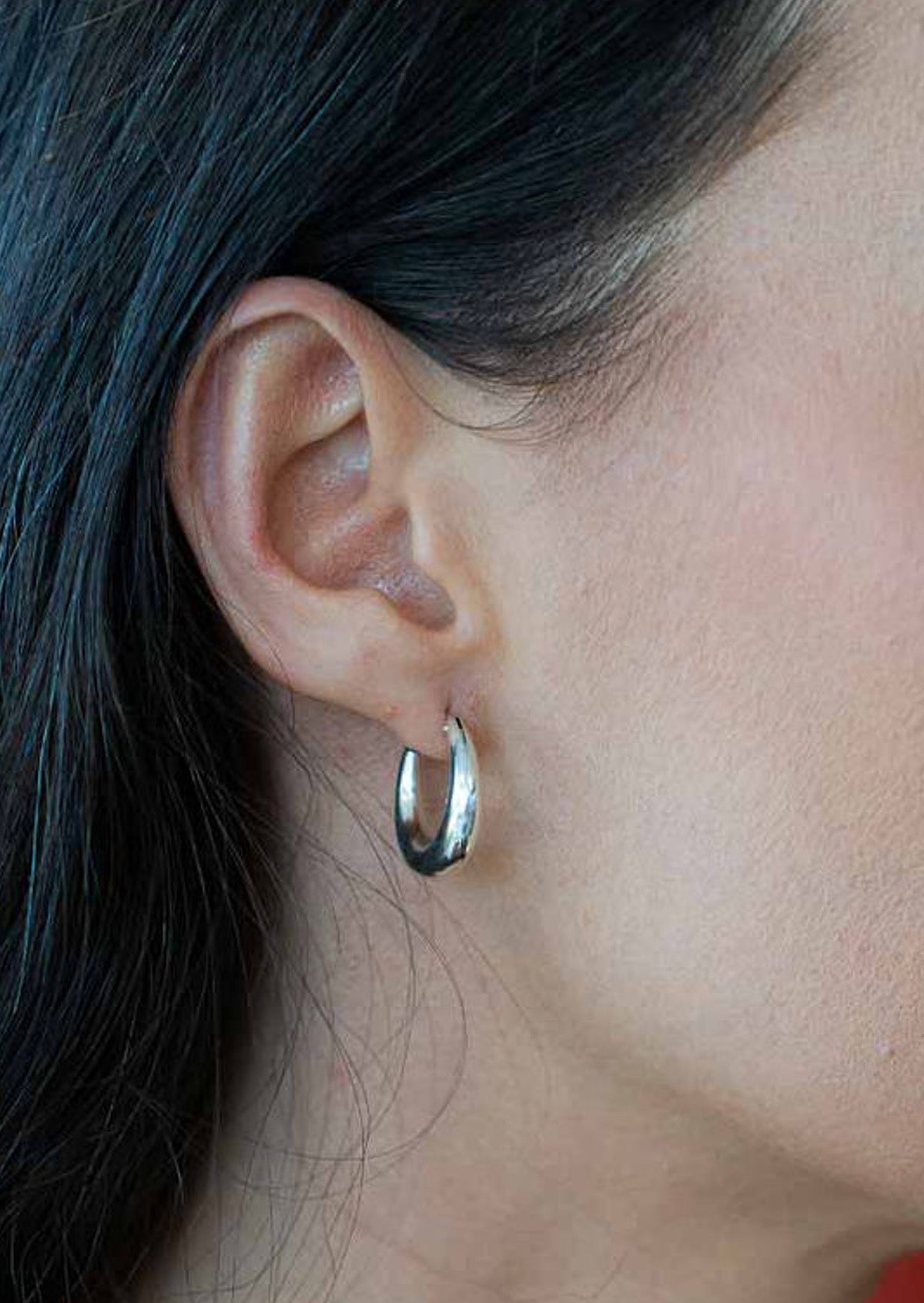 Medium sized silver hoop earrings on woman's ear