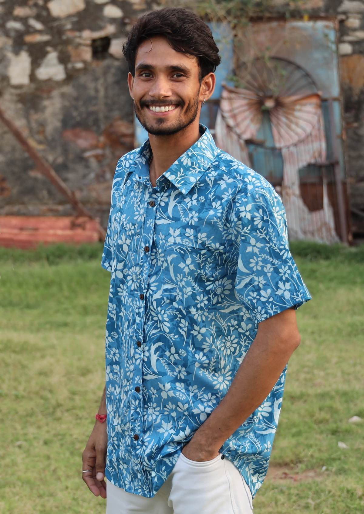 Man poses in a relaxed fit lightweight cotton shirt with short sleeves, collar and brown wooden buttons.
