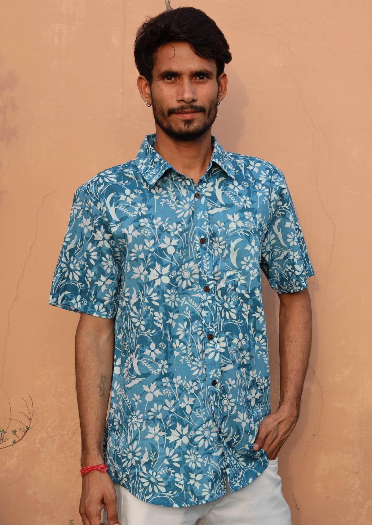 Man is wearing a 100% cotton collared shirt in pale blue based white floral print.