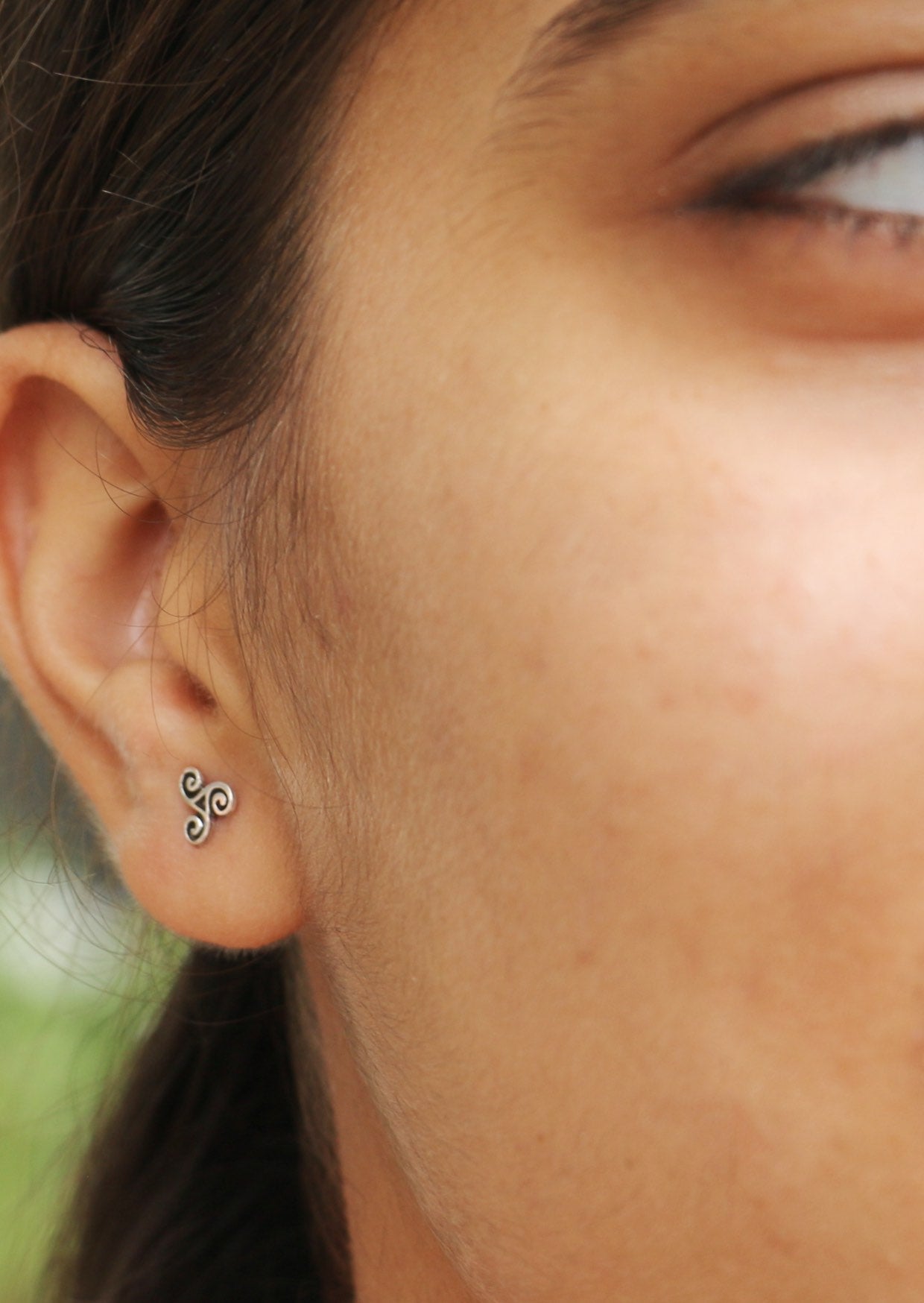 Close-up of an ear with a mini sterling silver Triskele studs with secure butterfly backs