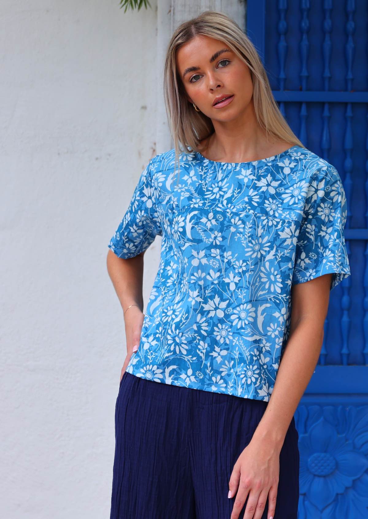 100% cotton blue floral blouse on woman with blonde hair in front of blue door