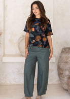 Woman wearing jungle green wide leg cotton pants with black floral top.