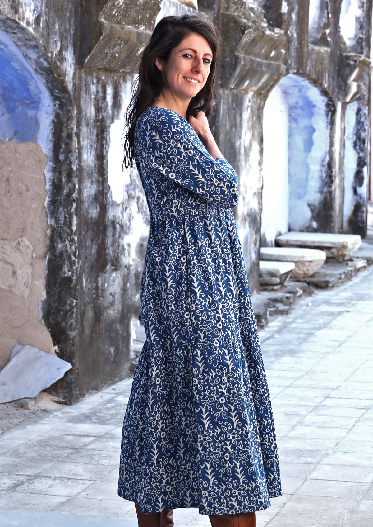 Model with dark hair wearing a cotton maxi dress with white floral print on blue base.