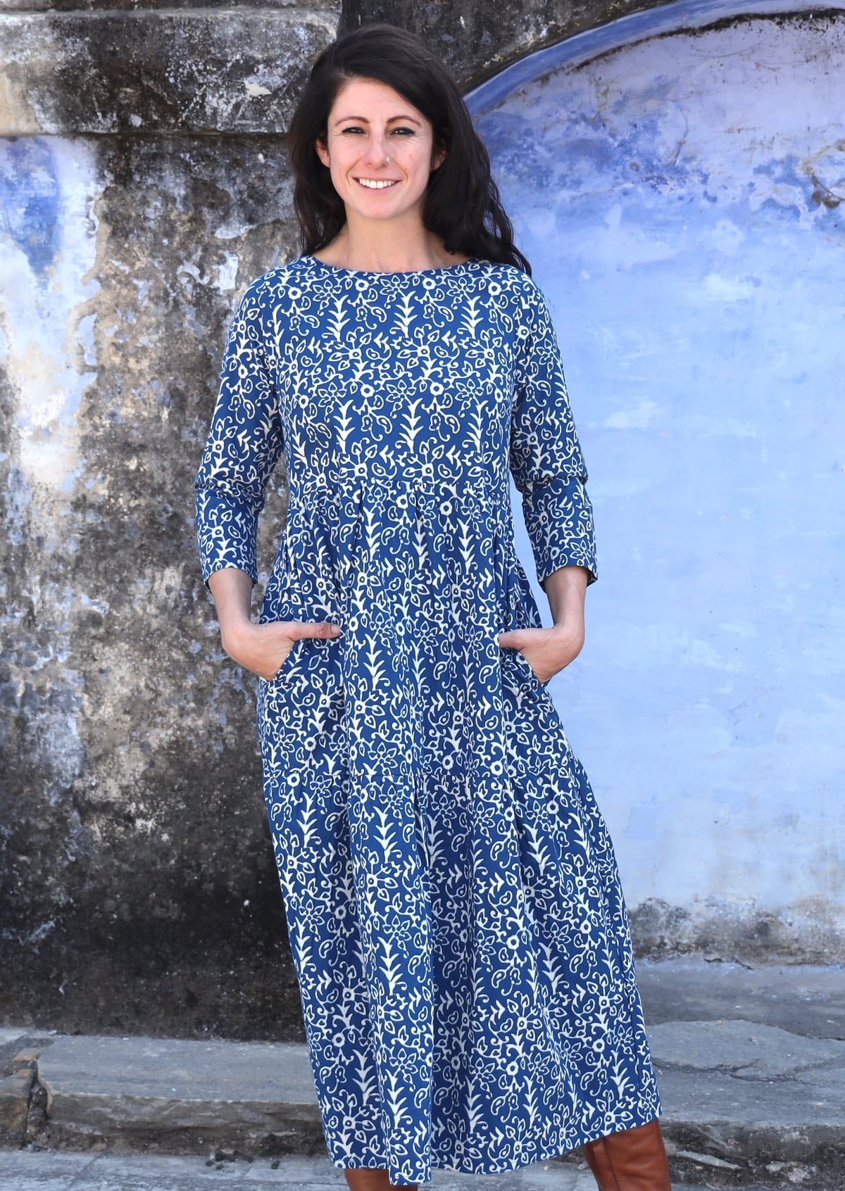 Model is wearing a blue cotton maxi dress with 3/4 sleeves and hands in the pockets.