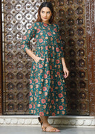 Model wearing a green cotton  three tiered midi length dress with green base and pink, cream and orange florals.