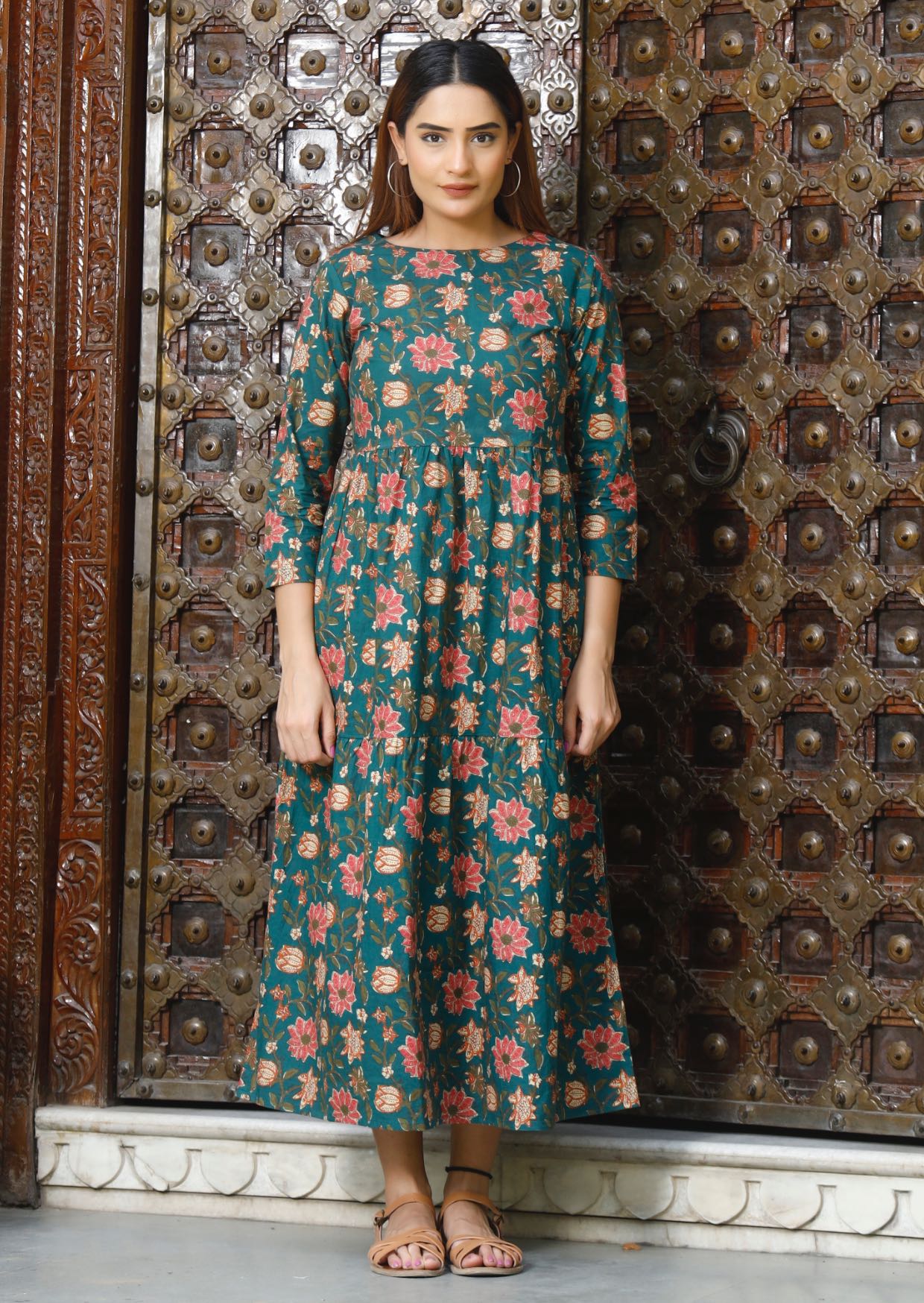 Model wears relaxed fit, midlength cotton dress in deep green based vibrant floral print.