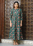 Model wears relaxed fit, midlength cotton dress in deep green based vibrant floral print.