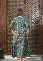 Model standing on back wearing a 3 tiered cotton dress with 3/4 sleeves and button back closure.