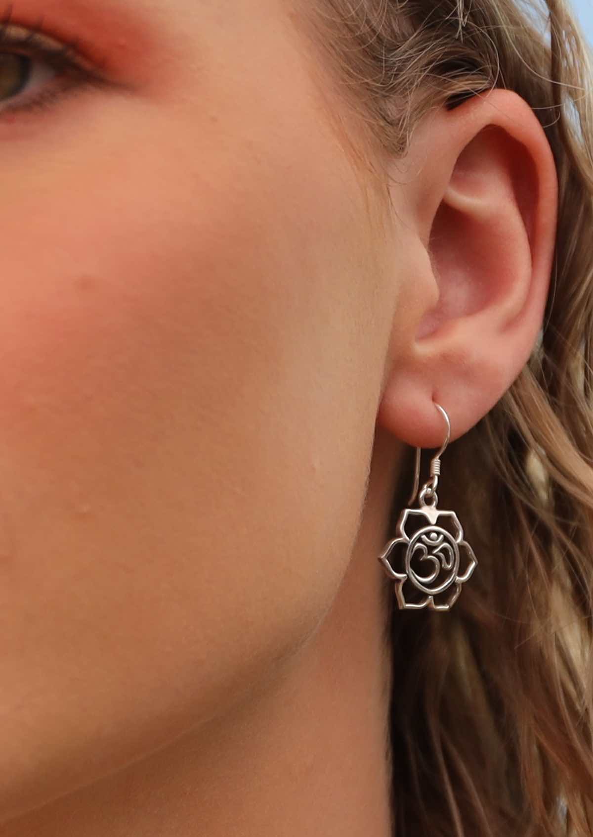 model wearing large silver om and flower design dangly earring