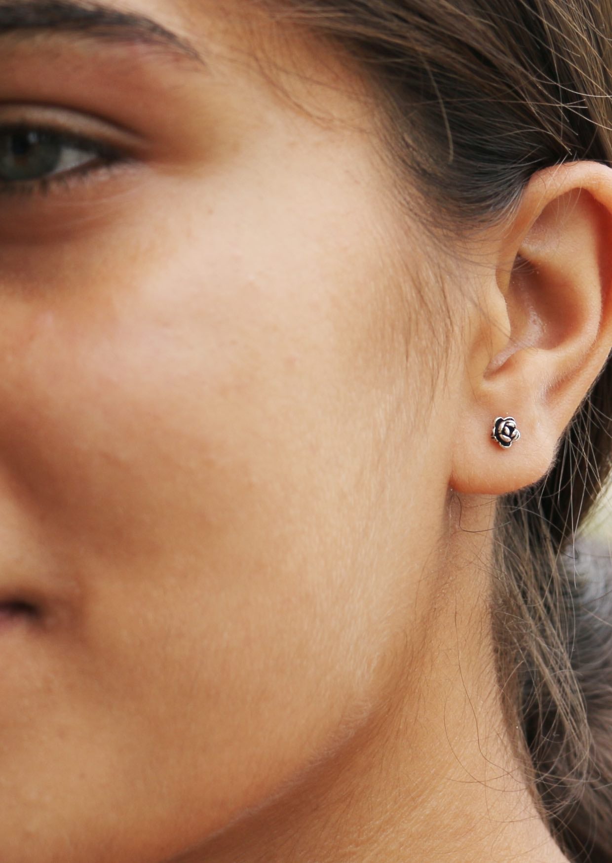 Close up of a person wearing delicate sterling silver peony studs with charming cluster of elegant flower petals