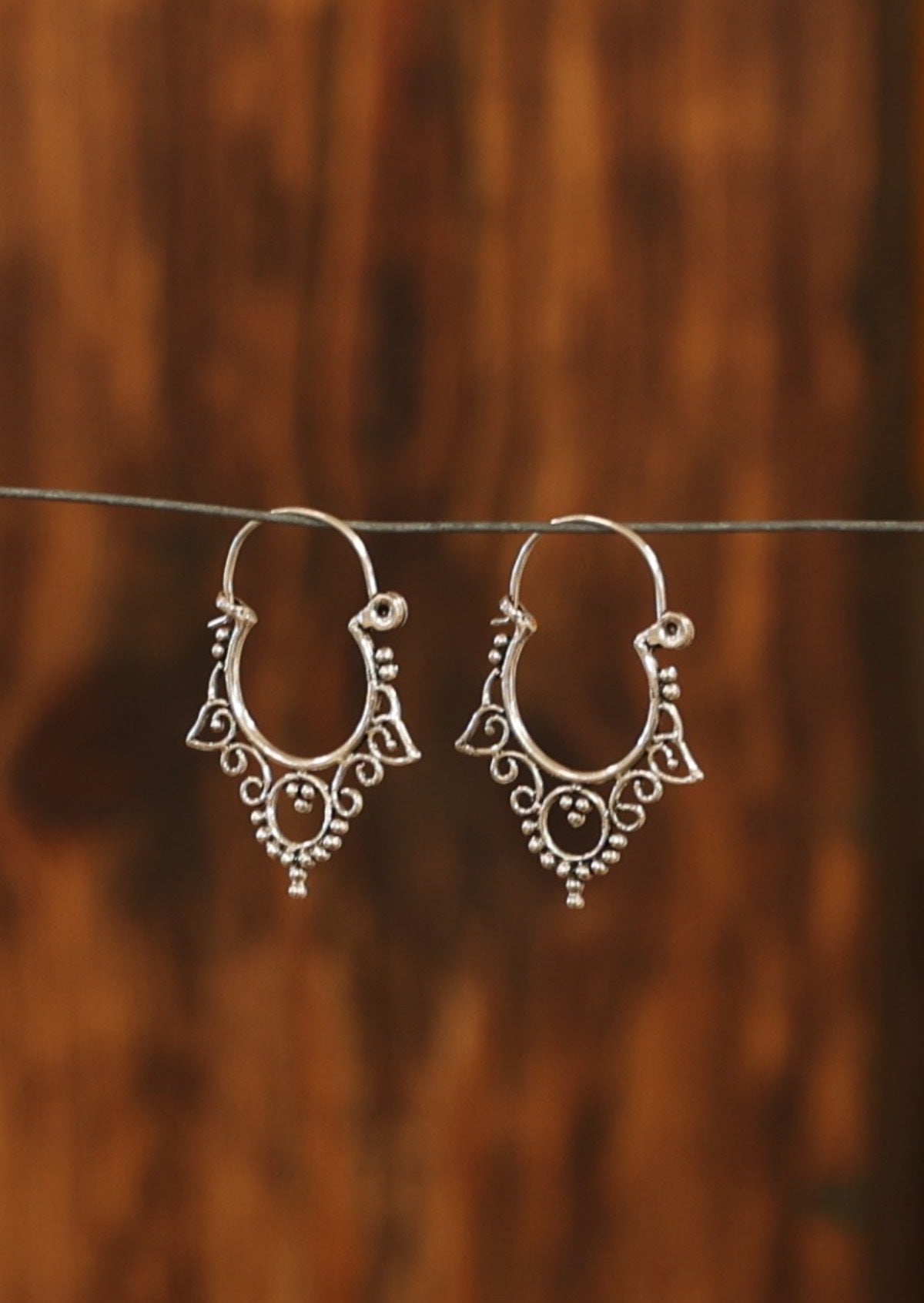 Sterling silver wire hoop earrings with spiral and bead detail on the underside of the hoop