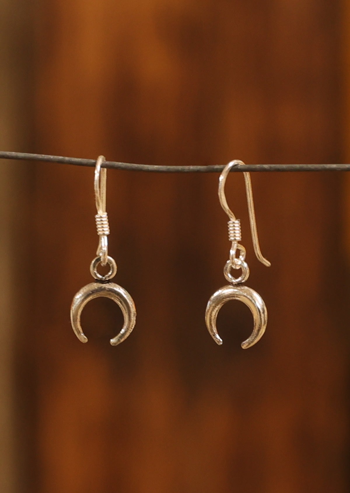 Sterling silver mini crescent moon earrings, suspended from wire hooks