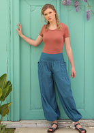 Model wears 100% cotton, loose fitting blue pants with pockets.