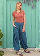 Blonde woman wears loose fitting boho pants and has her hand in the pocket.