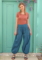 Blonde woman pairs lightweight boho pants with sandals and a short sleeve top.