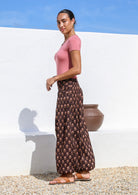 Model stands on side pairing floral printed brown cotton pants with round neck stretch top in pink.
