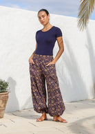 Model stands with hands in deep pockets wearing 100% cotton harem pants with wide waistband and elasticated ankles.