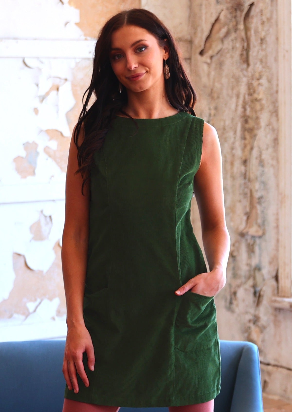 Woman wearing cotton corduroy tunic in Douglas Fir green with boat neck with hand in pocket