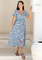 Woman wearing a relaxed fit blue floral cotton dress standing in a bright room.