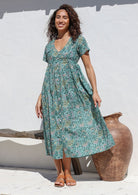 Model wears sage green floral print  midlength cotton dress with V neckline, button front, shoestring tie at empire waist and pockets