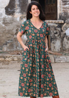 woman in green cotton floral v neck maxi dress with hands in pockets
