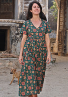 Model smiling wearing 100 percent cotton dark jade green button through v-neck dress with pockets