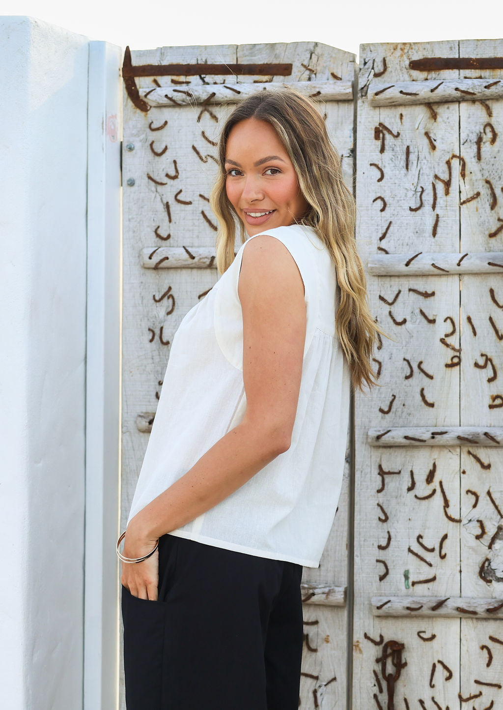 Model wears natural white cotton sleeveless top with gathers across the bust