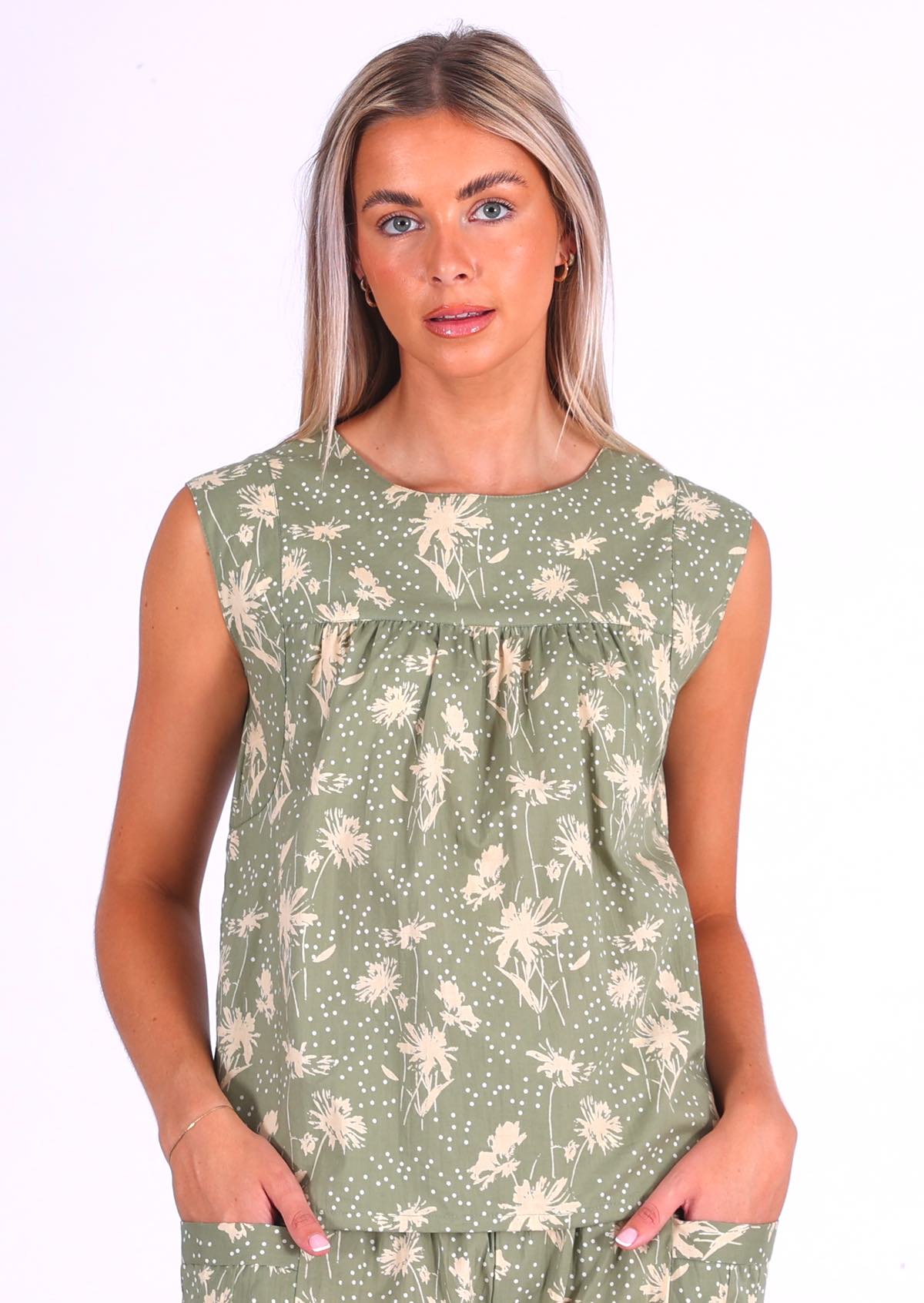 Woman wears pale green cotton sleeveless top with small gathers across the bust