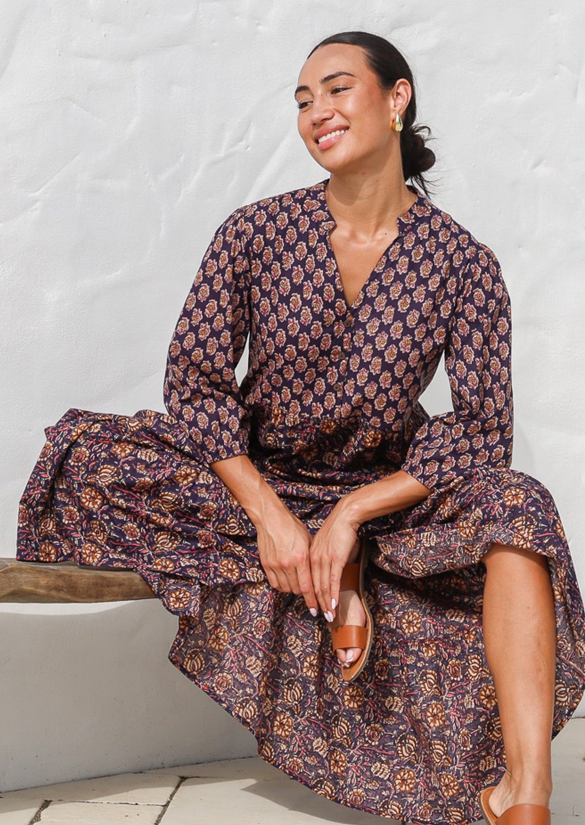 Model seated in a beautiful floral printed cotton maxi dress with buttoned bodice, 3/4 sleeves and V neckline.