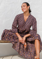 Model seated in a beautiful floral printed cotton maxi dress with buttoned bodice, 3/4 sleeves and V neckline.