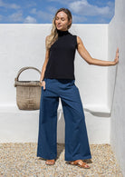 A woman wears 100% cotton wide-legged, high-waisted pants in sea blue, paired with a sleeveless basic black rayon top