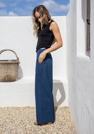 Model wearing a 100% cotton wide leg pants in dark sea blue with wide waistband and a side zipper