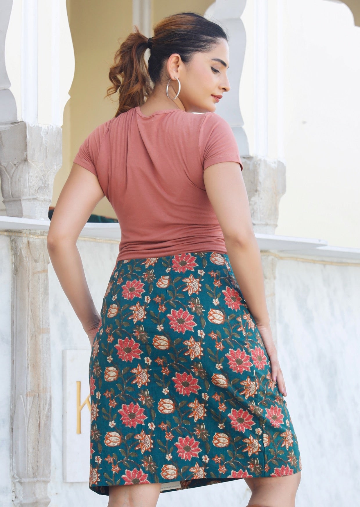 Woman stands in back pose wearing a knee length cotton reversible skirt with hidden side zipper.